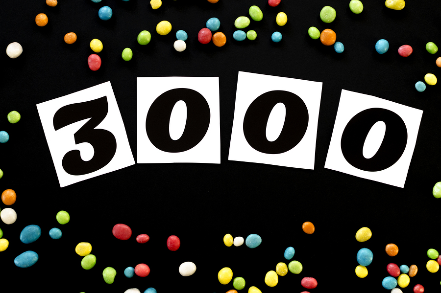number 3000 with multicolored candy around on black background
